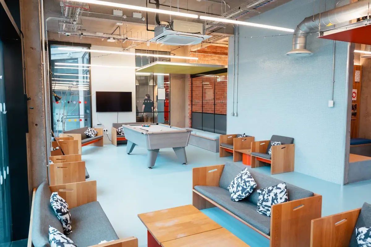Bright social room in Beton House showing seating area and pool table.