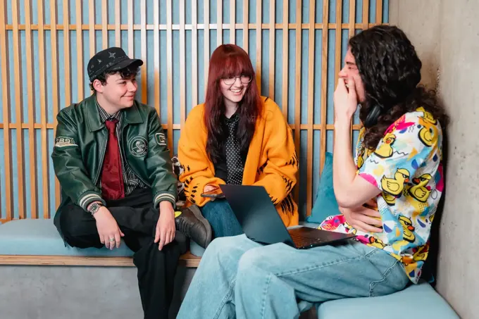 3 students sat chatting on a corner bench